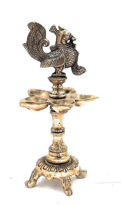 Brass Peacock Diya with Four Lamps on Stand in Gold Color Color: An exquisite diya featuring four lamps in a peacock - SvarupArt
